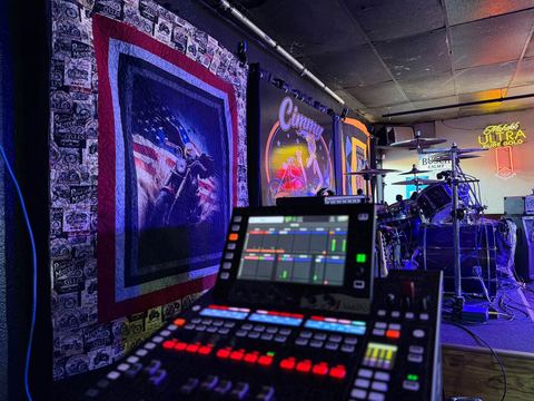 Stage with a line-array speaker stack, drum kit and digital mixing console in a themed room