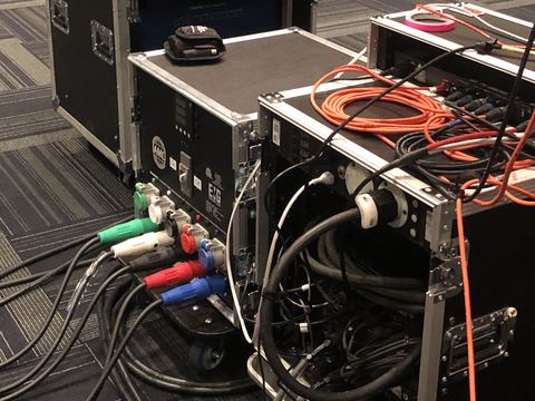 Road cases with rack gear and a power panel, with colored feeder cables and an orange cable plugged in